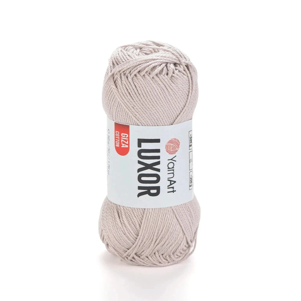 Ovillo de hilo YarnArt Luxor 100% algodón mercerizado Giza color beige claro en fondo blanco.