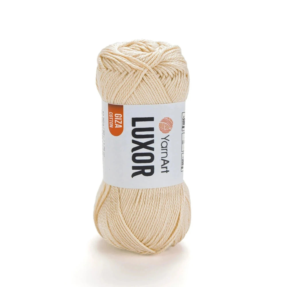 Ovillo de hilo YarnArt Luxor de algodón mercerizado, color beige claro, con etiqueta de marca visible sobre fondo blanco.