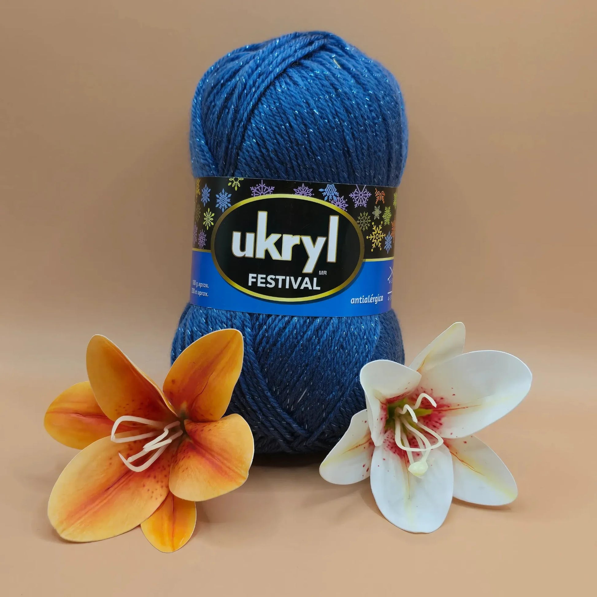 Ovillo de lana Ukryl Festival azul con lúrex brillante, 94% acrílico, junto a dos flores decorativas.