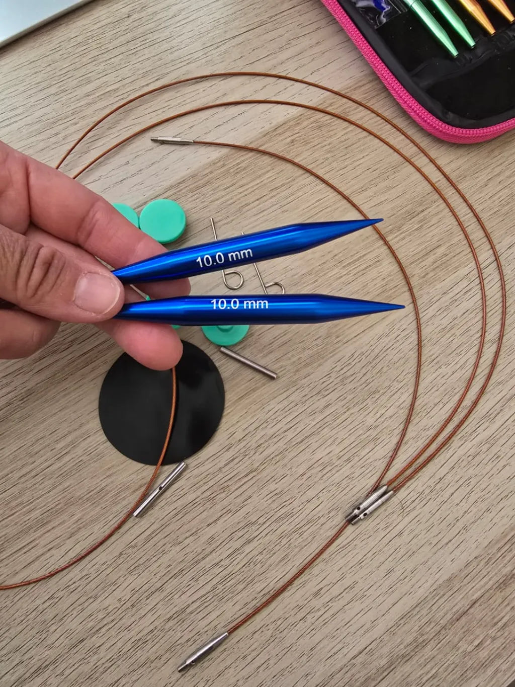 Set de palillos circulares intercambiables de aluminio azul 10.0 mm con cables y accesorios de tejido sobre mesa de madera.