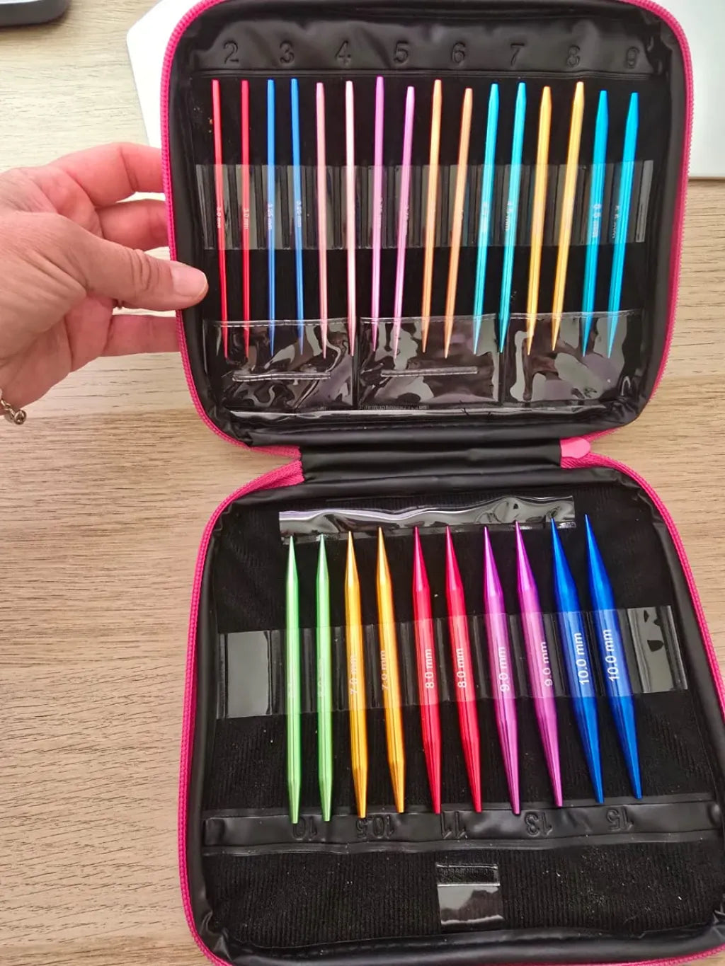 Set de palillos circulares intercambiables de aluminio en estuche rosa, con agujas de tejer en vibrantes colores y distintas medidas.